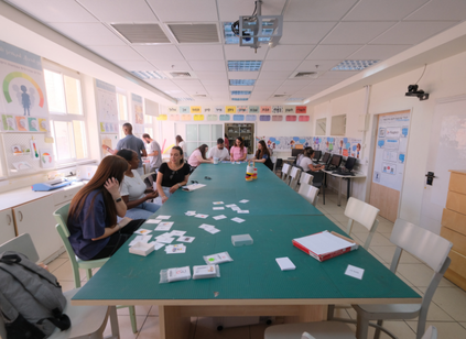 סטודנטים בסדנת למידה במכללה יושבים בשולחן ועובדים עם קלפים